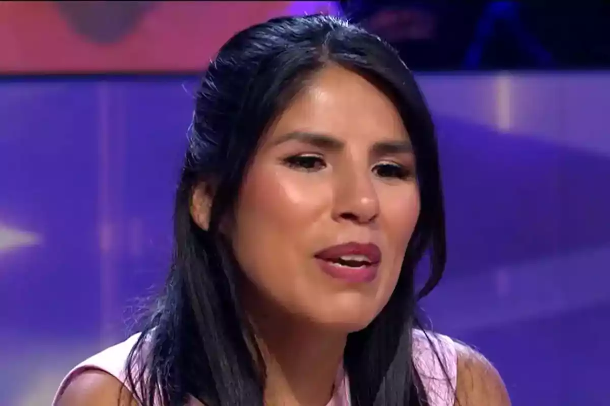 Una persona con cabello oscuro y lacio en un entorno iluminado con luces de fondo.