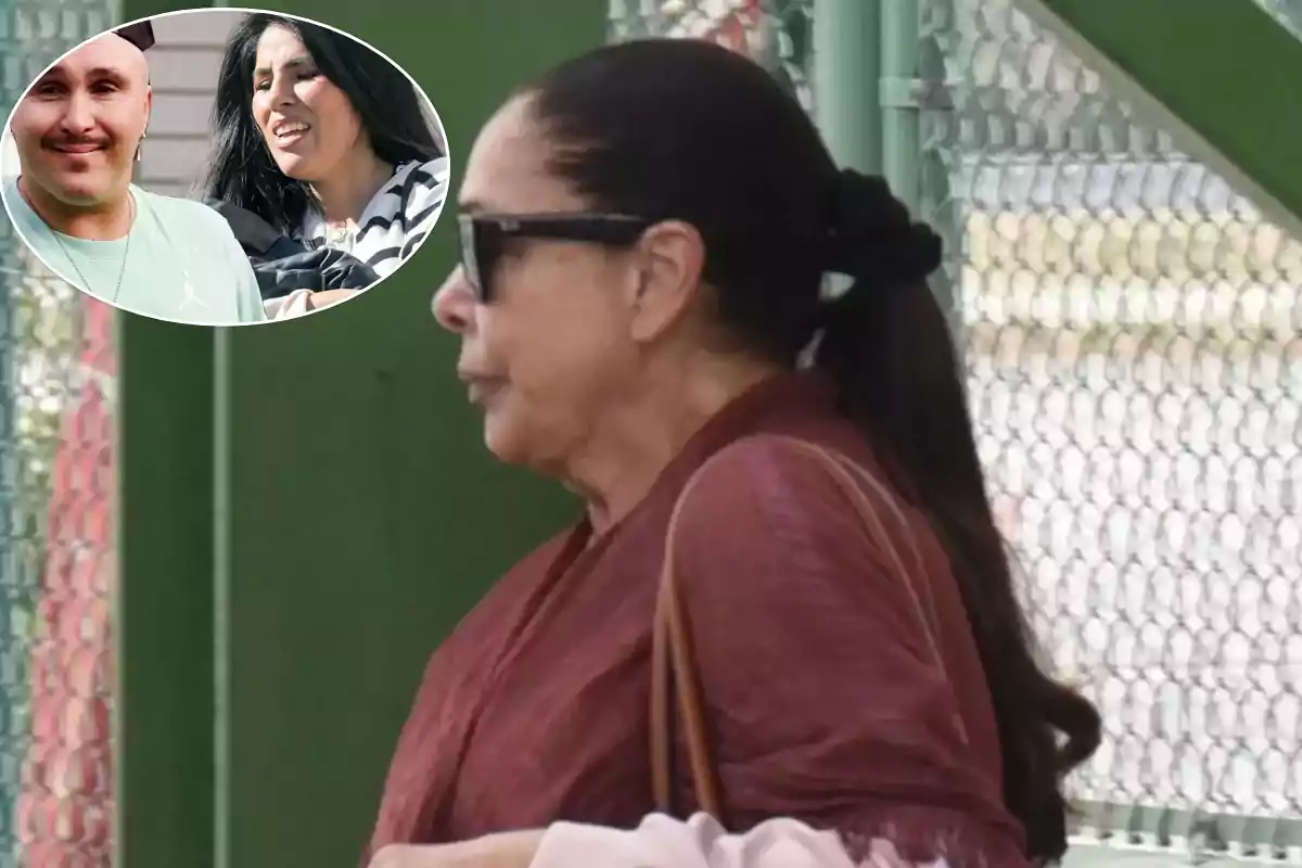 Una mujer con gafas de sol y cabello recogido camina junto a una cerca de alambre, en la esquina superior izquierda hay un recuadro con dos personas sonriendo.