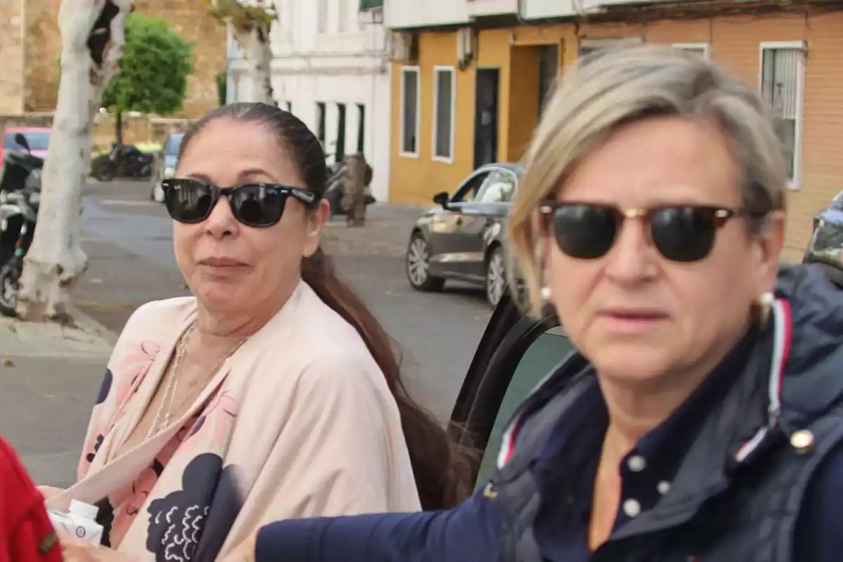 Dos mujeres con gafas de sol en una calle urbana.
