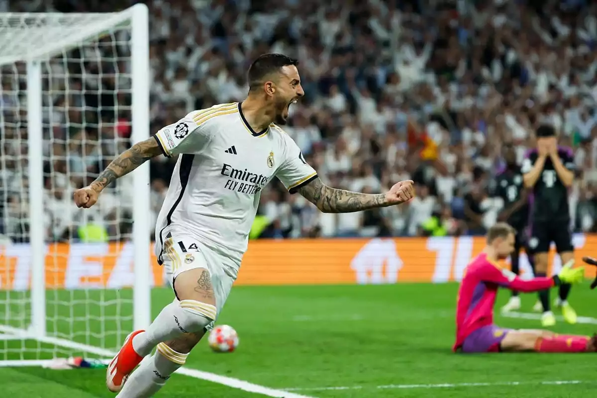 Jugador de fútbol celebrando un gol en un partido, con el portero y otros jugadores del equipo contrario en el fondo.