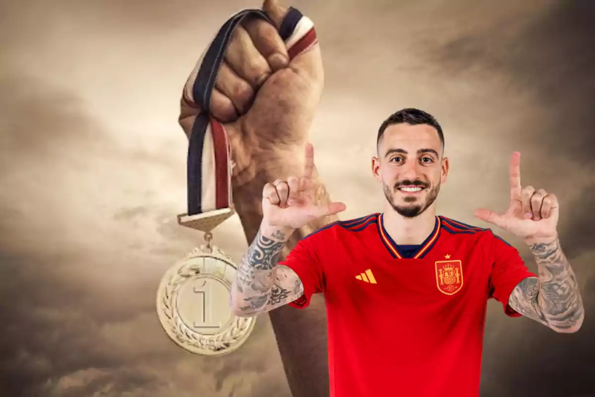 Un hombre con una camiseta roja de la selección española de fútbol hace un gesto con las manos mientras una mano en el fondo sostiene una medalla de oro.