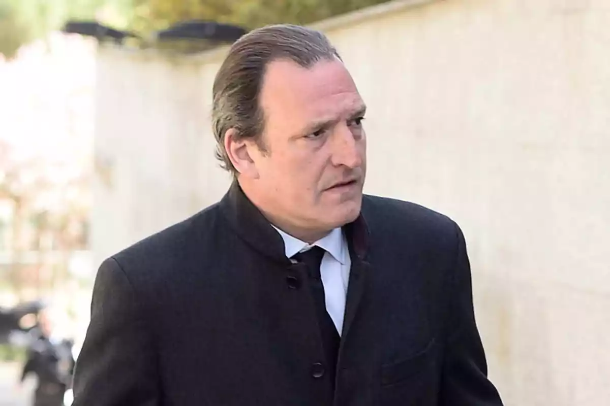 Hombre con abrigo oscuro y corbata negra caminando al aire libre. Hombre con abrigo oscuro y corbata negra caminando al aire libre.