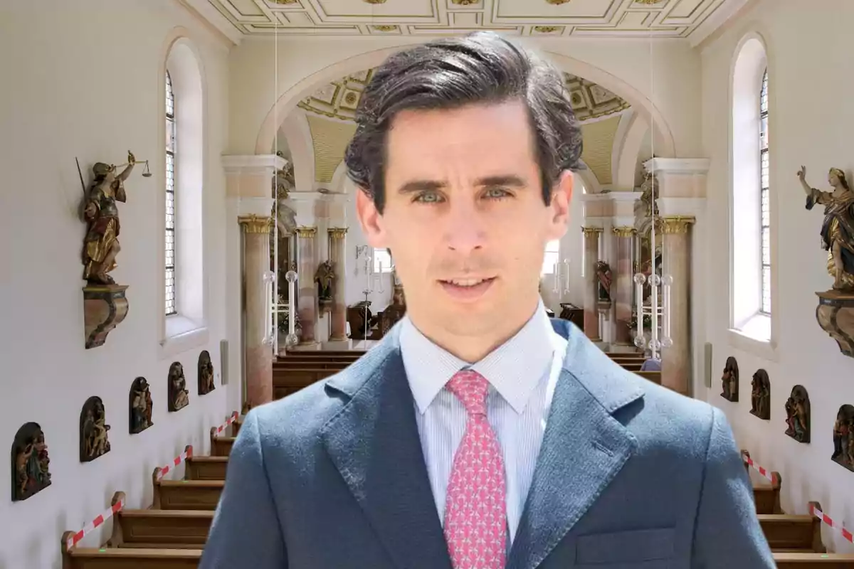 Hombre de traje y corbata rosa en el interior de una iglesia decorada con estatuas y vitrales.