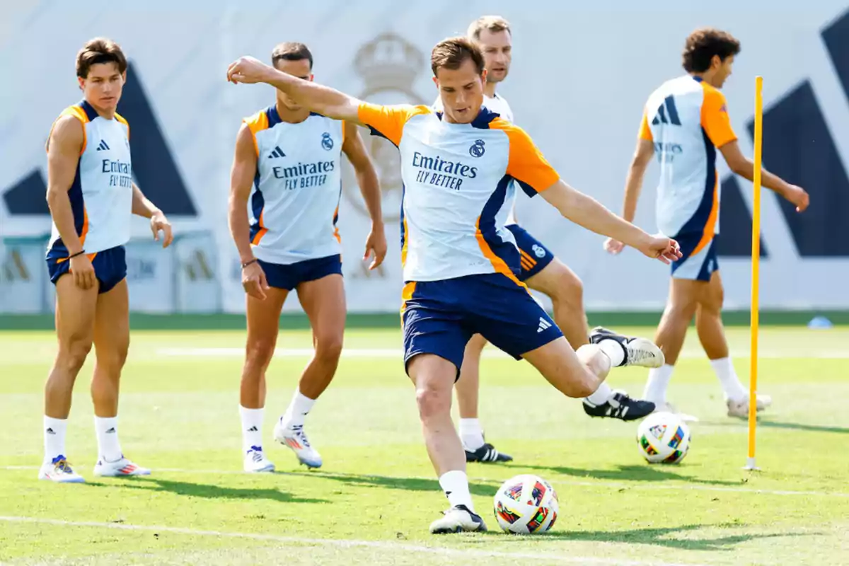 Jugadores de fútbol del Real Madrid entrenando en el campo con uniformes de entrenamiento blancos y naranjas. Jugadores de fútbol del Real Madrid entrenando en el campo con uniformes de entrenamiento blancos y naranjas.