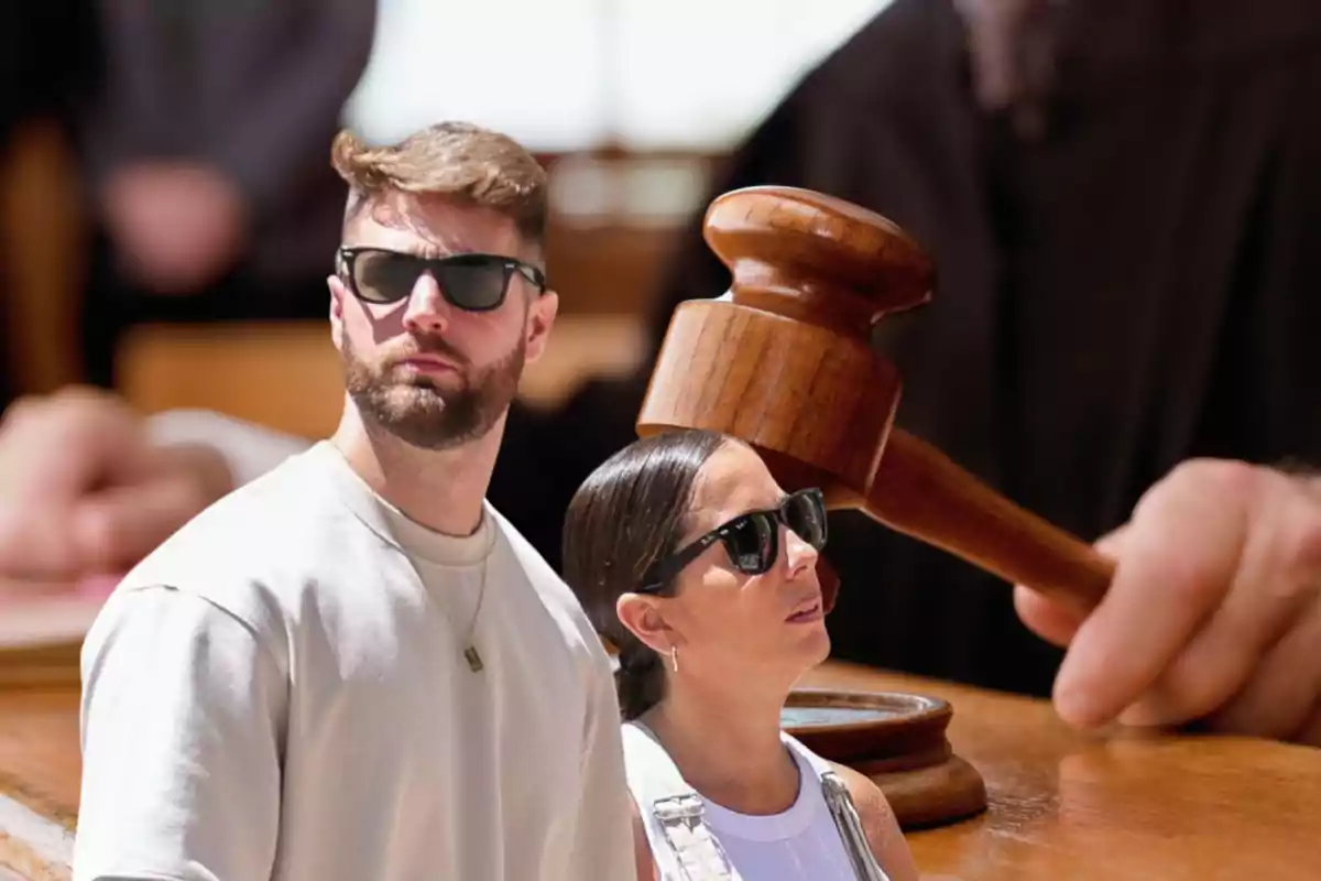 Dos personas con gafas de sol frente a un mazo de juez en un entorno de tribunal.