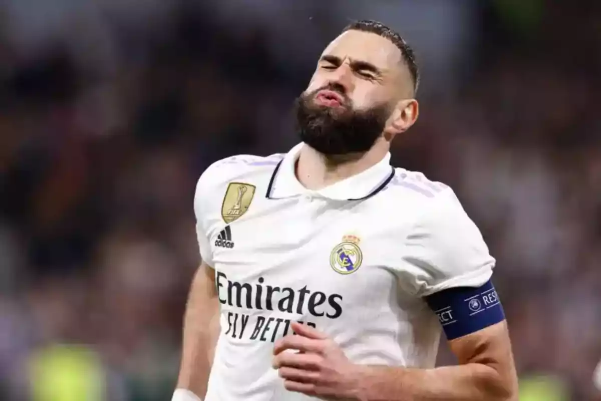 Jugador de fútbol con uniforme blanco del Real Madrid y brazalete de capitán en el campo de juego.