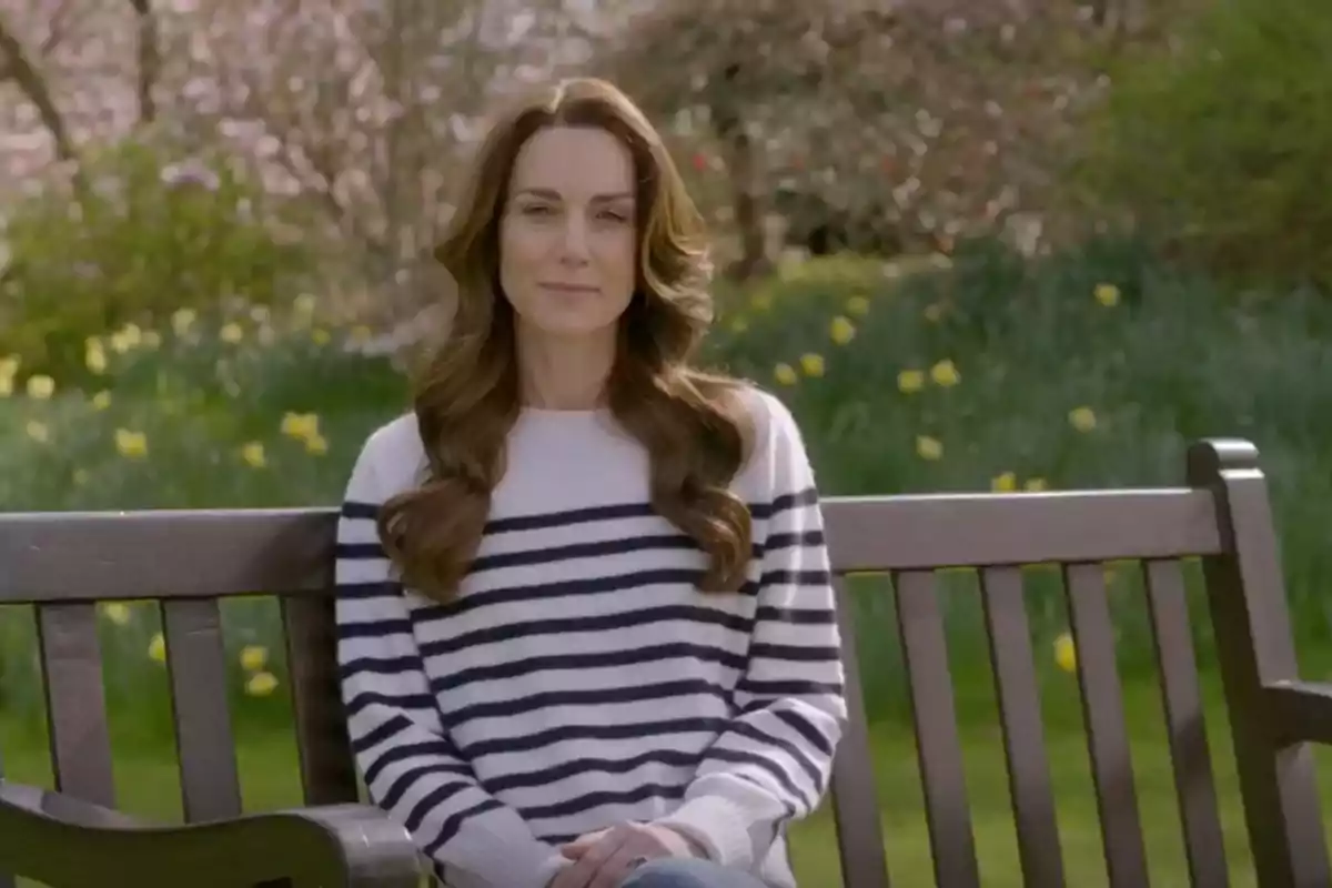 Kate Middleton sentada en un banco vestida con un jersey blanco con rayas negras