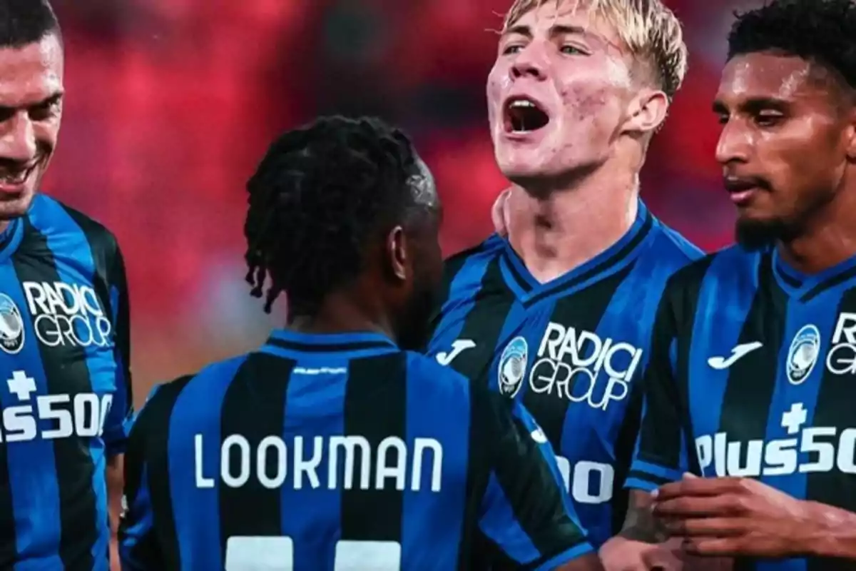 Jugadores de fútbol del Atalanta celebrando en el campo con camisetas azul y negro.