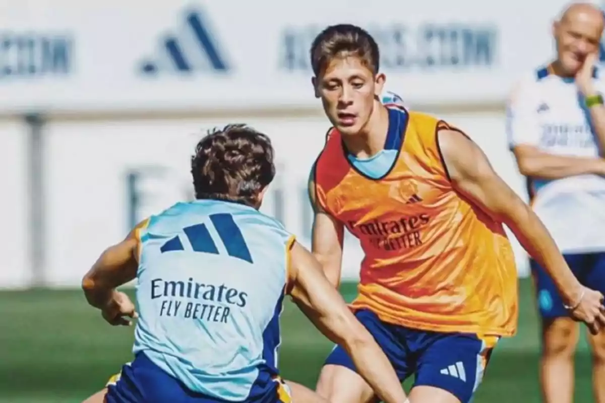 Jugadores de fútbol entrenando en un campo con petos de entrenamiento.