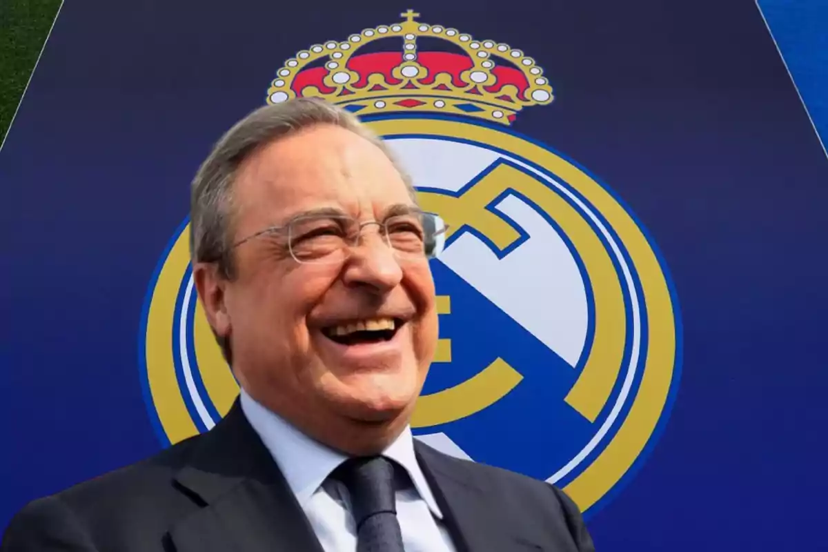 Un hombre sonriente con gafas y traje frente al escudo del Real Madrid.