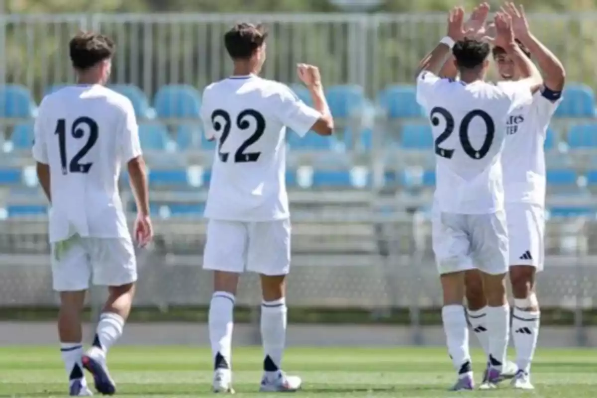 Jugadores de fútbol con uniformes blancos celebrando en el campo.