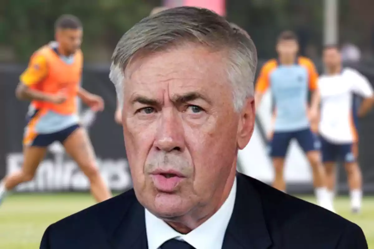 Carlo Ancelotti, con jugadores de fútbol entrenando en el fondo.