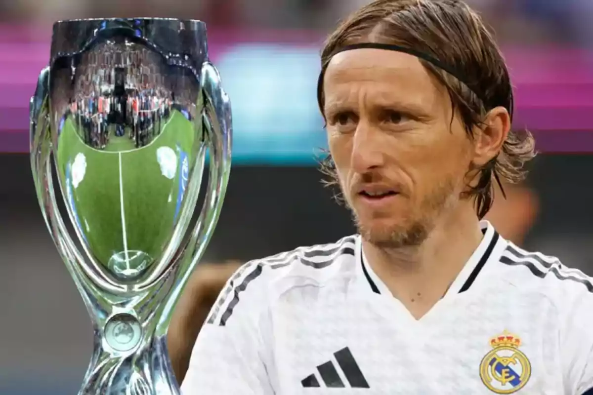 Modric con la camiseta del Real Madrid junto a un trofeo plateado.