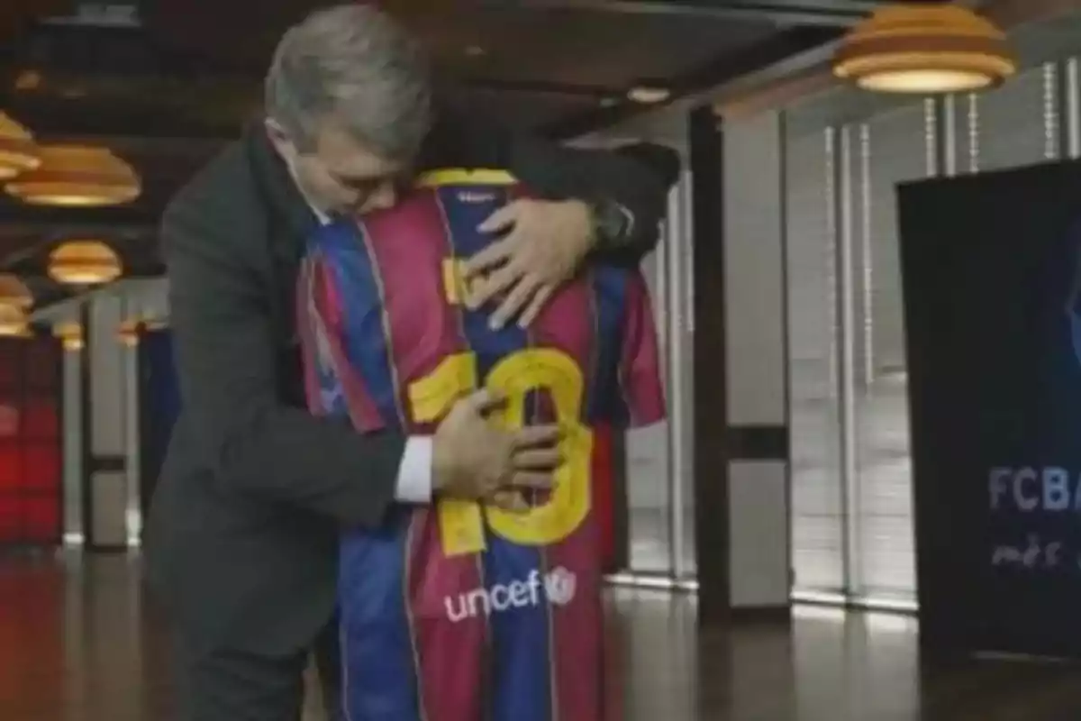 Un hombre abrazando a una persona que lleva una camiseta de fútbol con el número 10 en la espalda. Un hombre abrazando a una persona que lleva una camiseta de fútbol con el número 10 en la espalda.