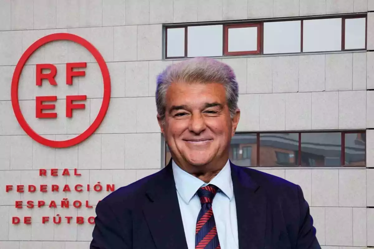 Un hombre sonriente con traje y corbata frente al edificio de la Real Federación Española de Fútbol.