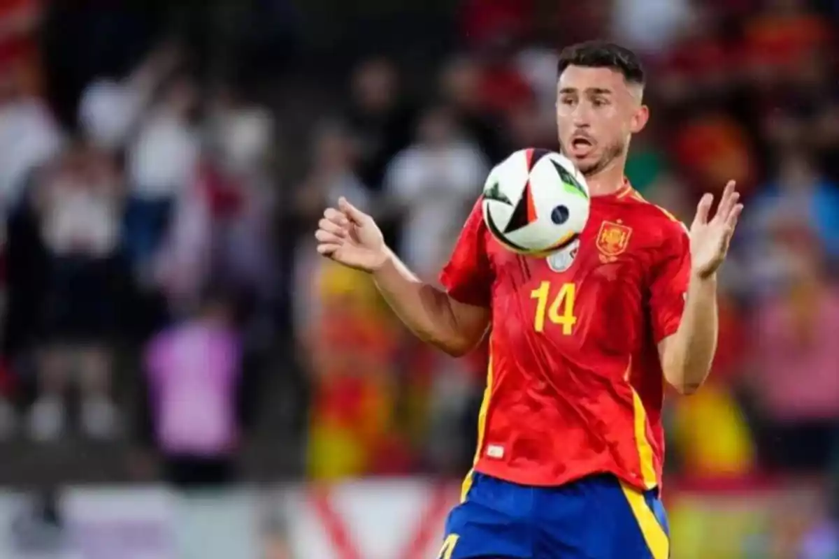 Jugador de fútbol con la camiseta roja de la selección española controlando un balón con el pecho durante un partido.