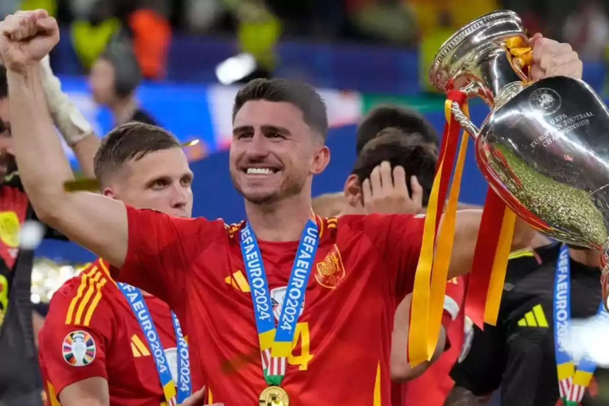 Un jugador de fútbol de la selección española levanta el trofeo de la UEFA Euro 2024 mientras celebra con sus compañeros.