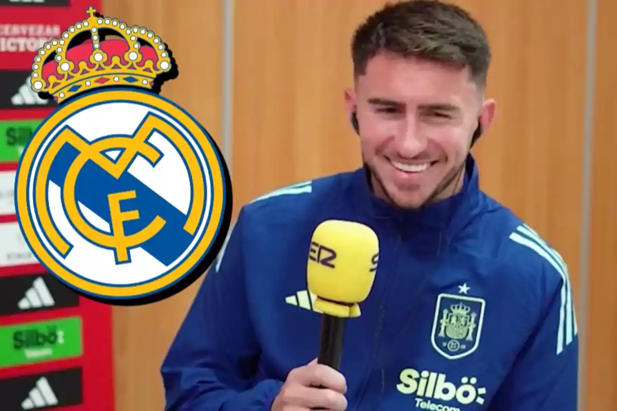 Un hombre con uniforme deportivo azul sostiene un micrófono amarillo frente a un fondo de madera y un logotipo del Real Madrid.