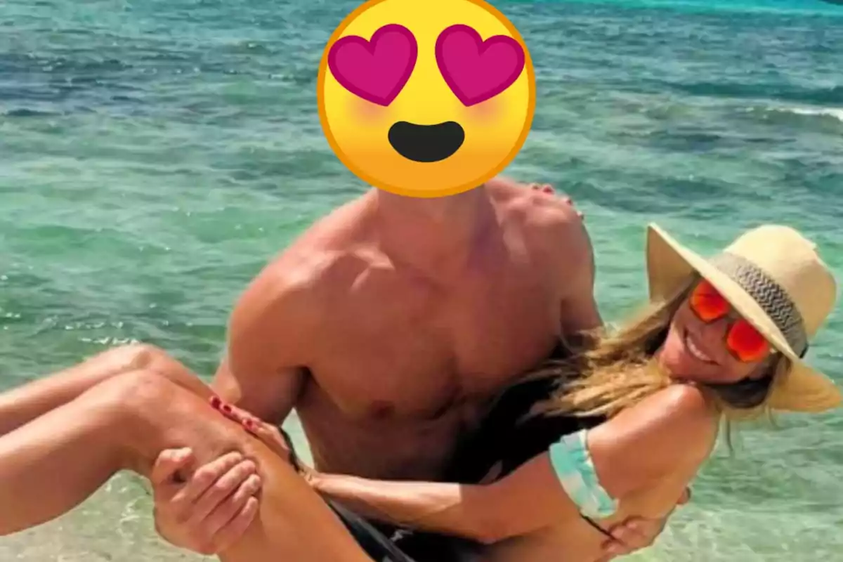 Una pareja disfrutando en la playa, con el hombre cargando a la mujer mientras ambos sonríen.