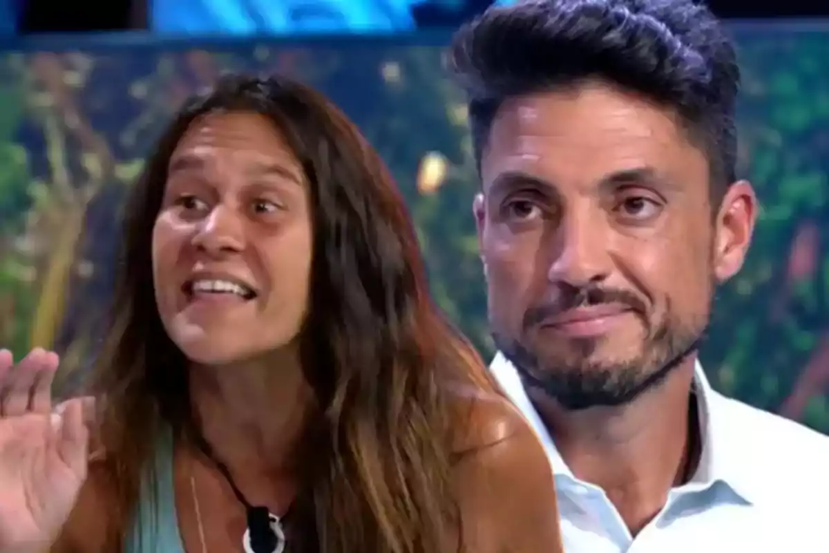 Dos personas en un programa de televisión con expresiones faciales intensas y un fondo colorido.