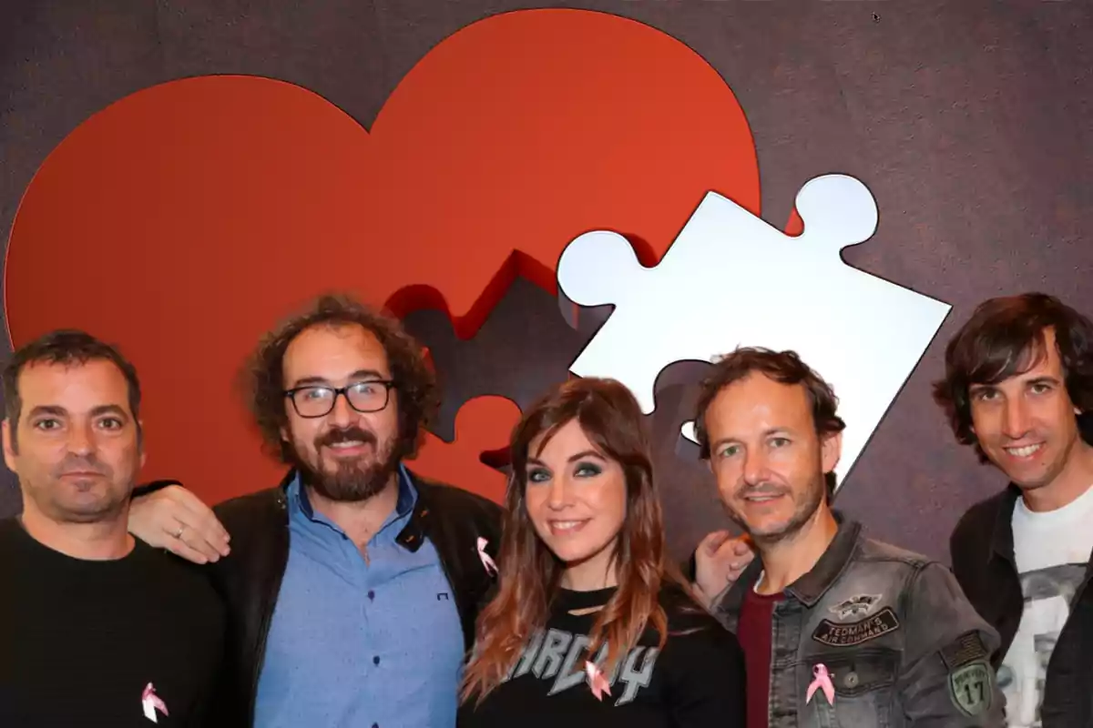 Un grupo de personas posando frente a un fondo con un corazón y una pieza de rompecabezas.