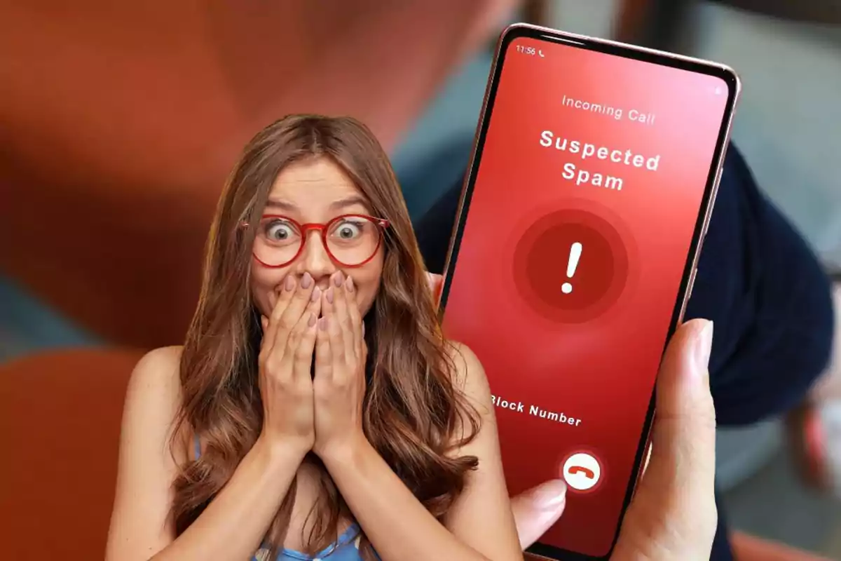 Una mujer con gafas rojas se cubre la boca sorprendida mientras sostiene un teléfono que muestra una alerta de llamada de spam sospechosa.