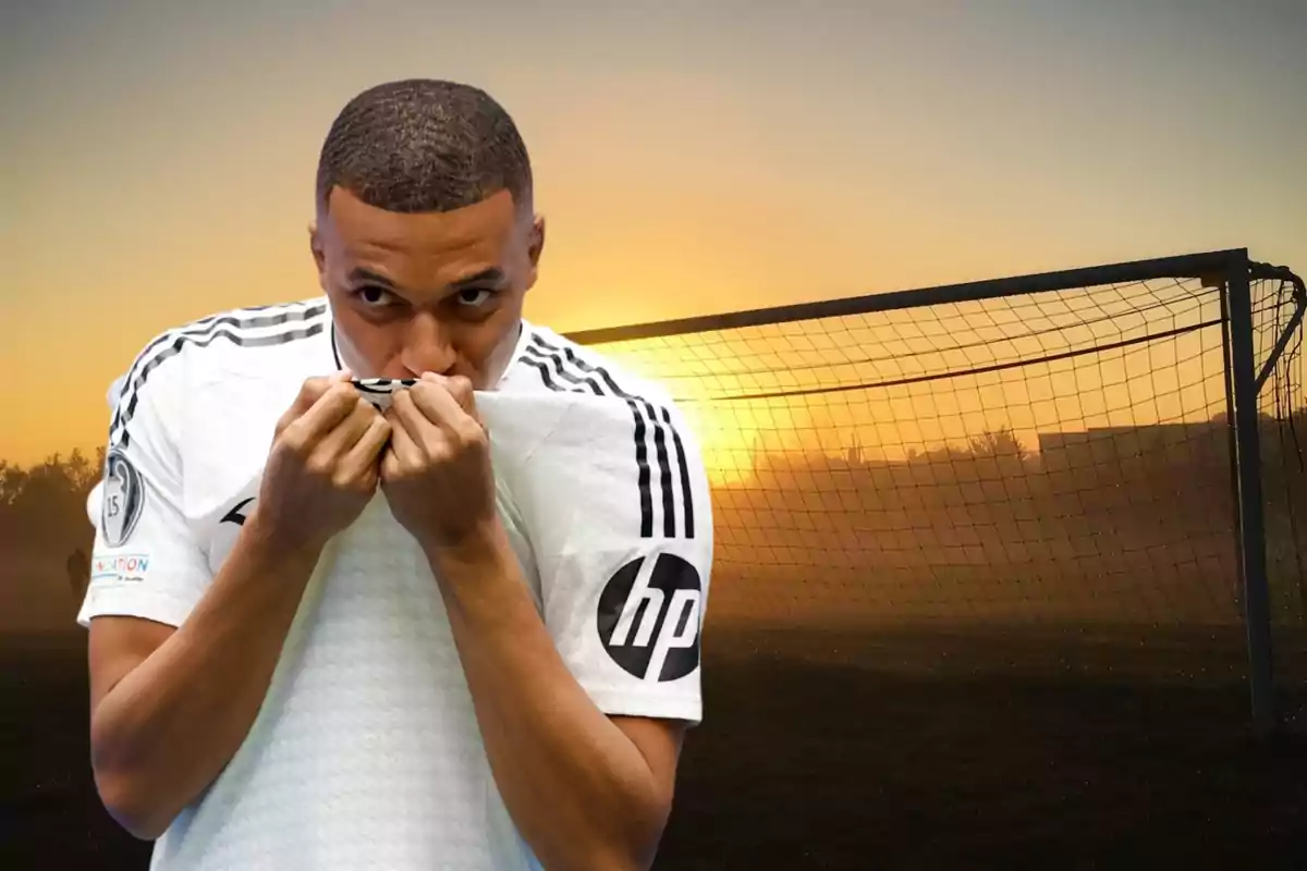 Un jugador de fútbol besando la camiseta frente a una portería al atardecer.