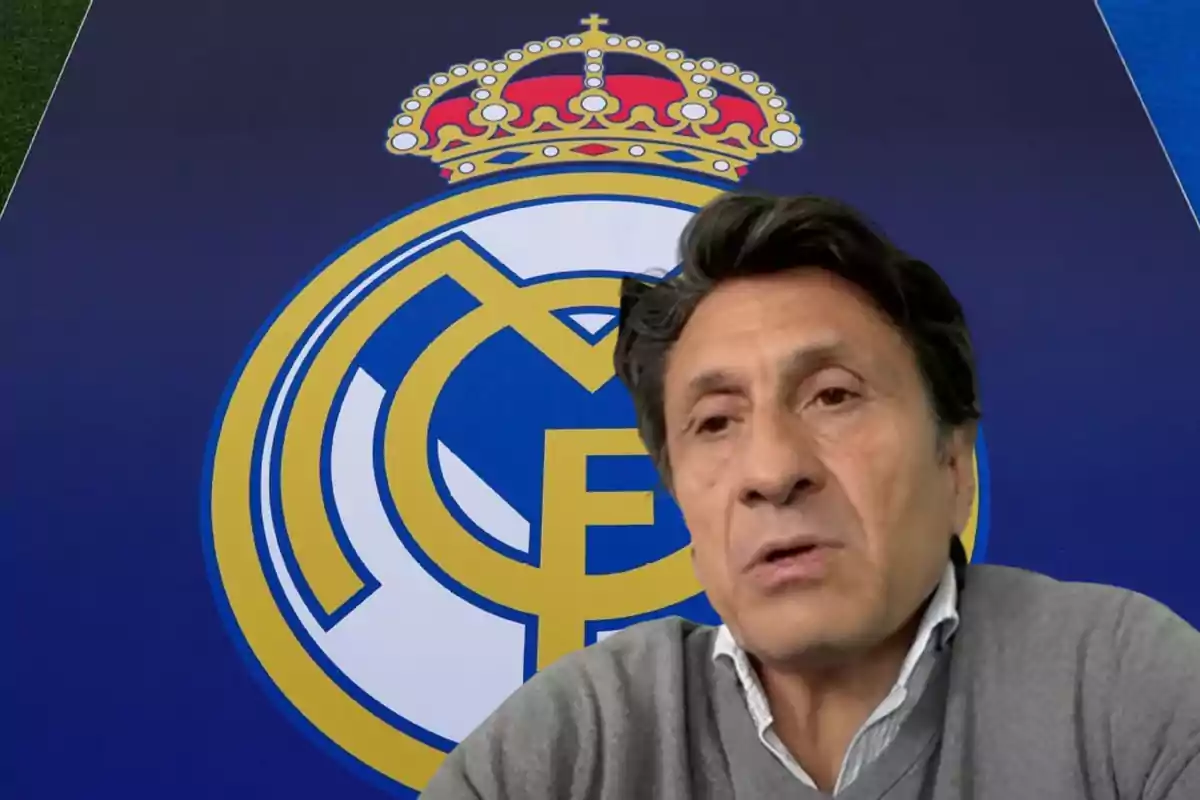 Un hombre con suéter gris frente al escudo del Real Madrid.