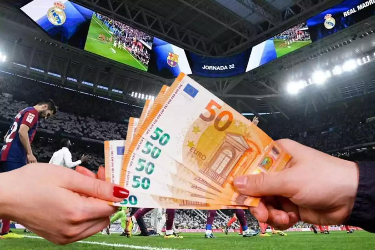 Una mano entrega billetes de 50 euros a otra mano en un estadio de fútbol con jugadores en el campo y pantallas mostrando un partido.