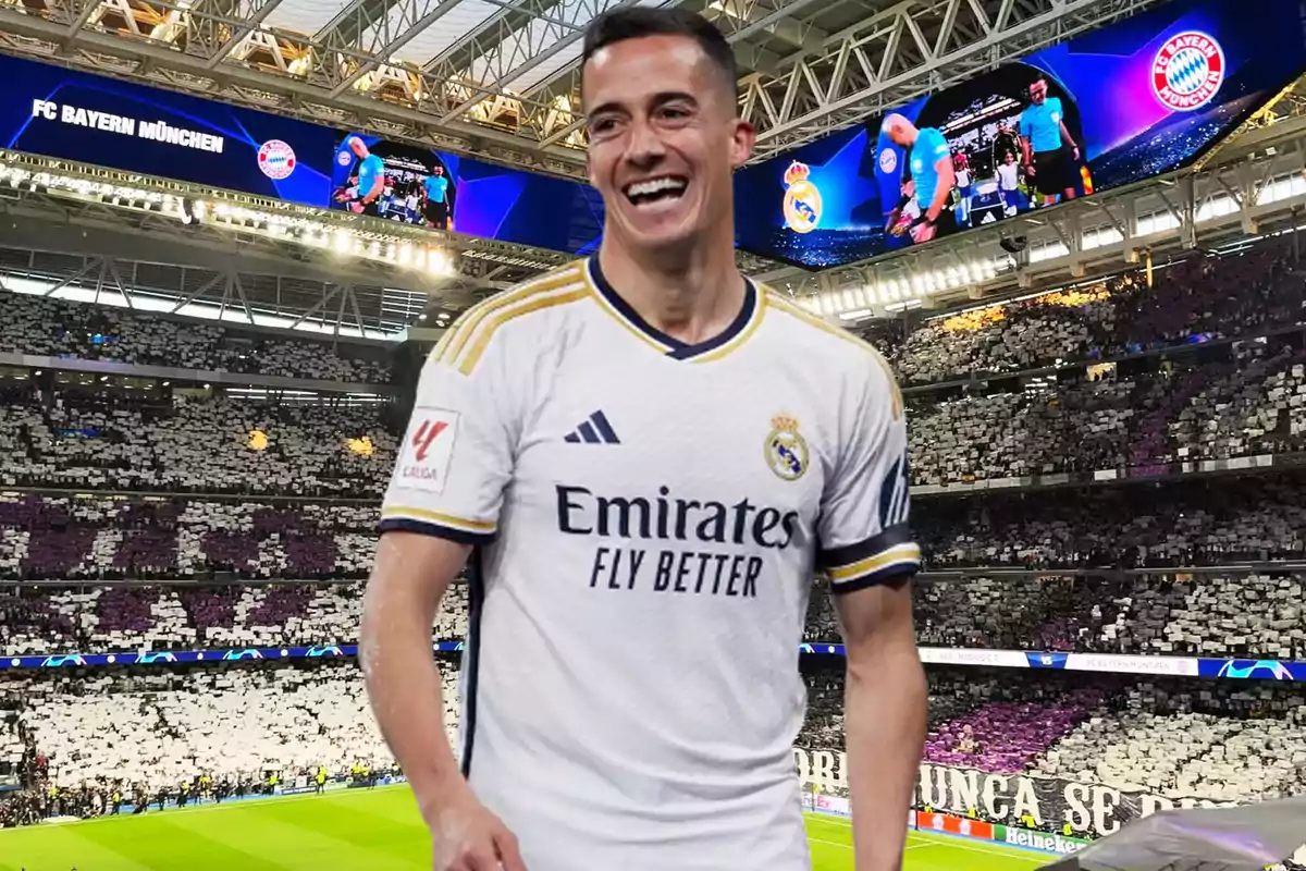 Un jugador de fútbol con la camiseta del Real Madrid sonríe en un estadio lleno de aficionados, con una pantalla que muestra el logo del FC Bayern München.