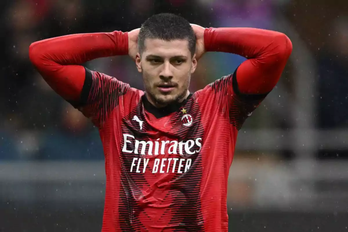 Jugador de fútbol con uniforme rojo y negro del AC Milan, con las manos en la cabeza durante un partido bajo la lluvia. Jugador de fútbol con uniforme rojo y negro del AC Milan, con las manos en la cabeza durante un partido bajo la lluvia.