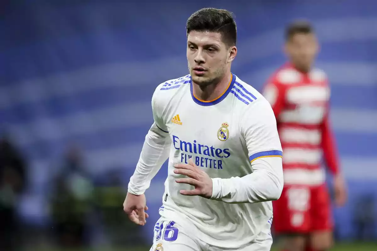 Un jugador de fútbol con uniforme blanco corre en el campo durante un partido. Un jugador de fútbol con uniforme blanco corre en el campo durante un partido.