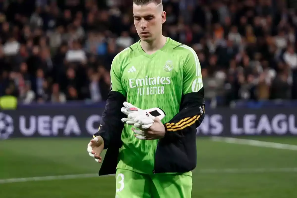 Portero de fútbol con uniforme verde sosteniendo guantes en un estadio durante un partido de la UEFA Champions League.