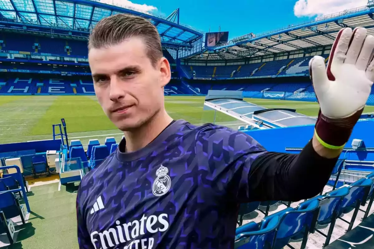 Un jugador de fútbol con uniforme de portero del Real Madrid levanta la mano en un estadio vacío.