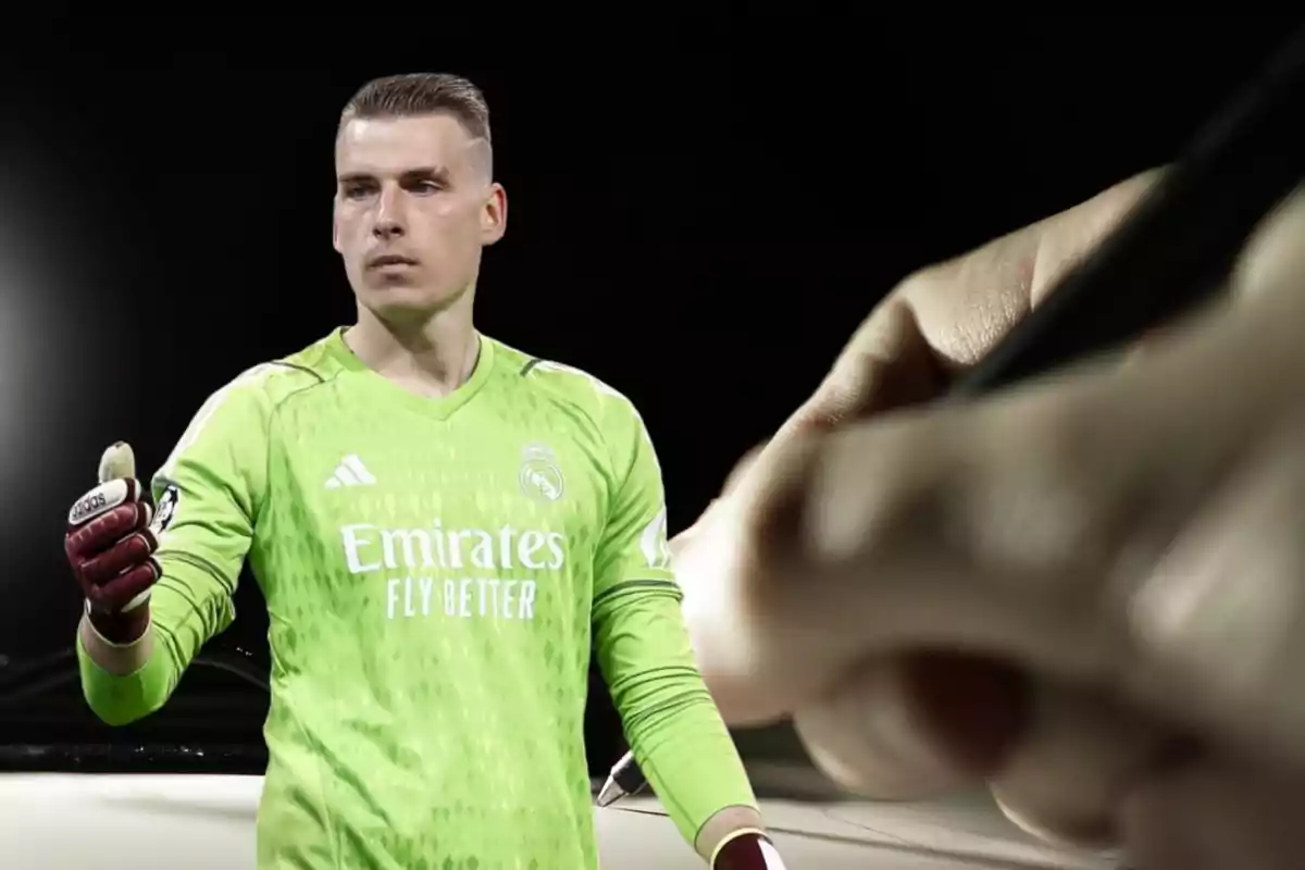 Un portero de fútbol con uniforme verde del Real Madrid, con guantes rojos, aparece en primer plano mientras una mano sostiene un bolígrafo en el fondo.