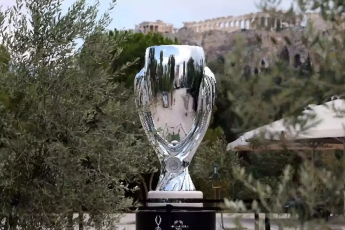 Trofeo de la Supercopa de la UEFA en exhibición al aire libre con el Partenón de Atenas al fondo.