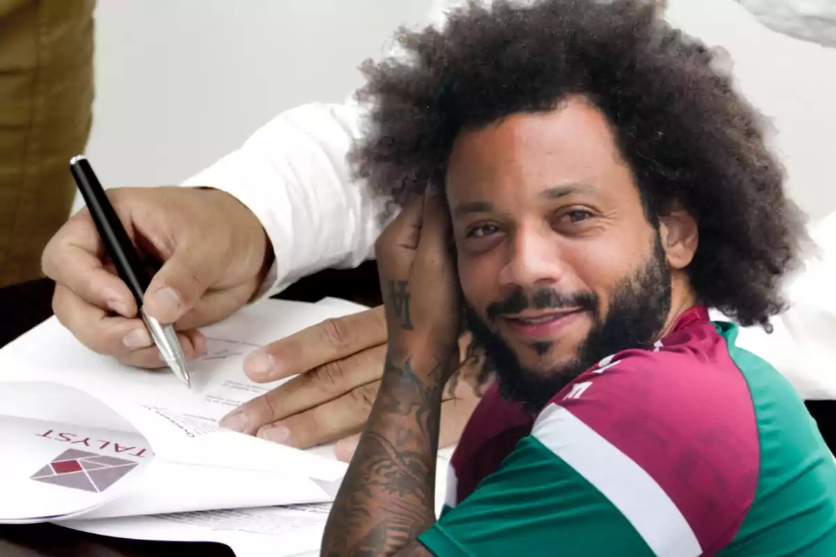 Un hombre sonriente con cabello rizado y barba está frente a una imagen de manos firmando un documento.