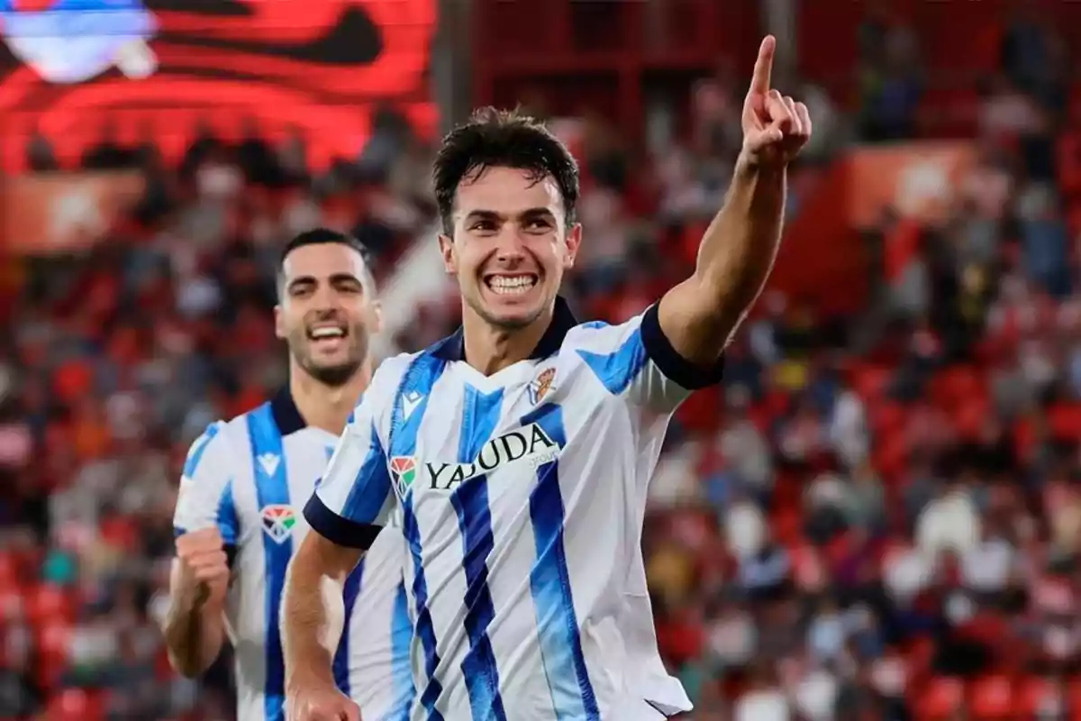 Jugadores de fútbol celebrando un gol en un estadio lleno de espectadores.