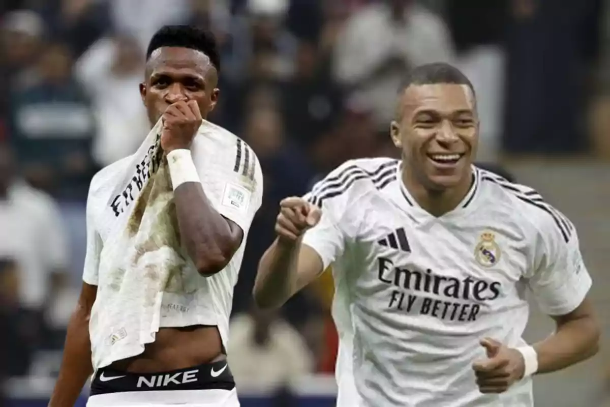 Dos futbolistas con camisetas blancas celebran en el campo de juego.