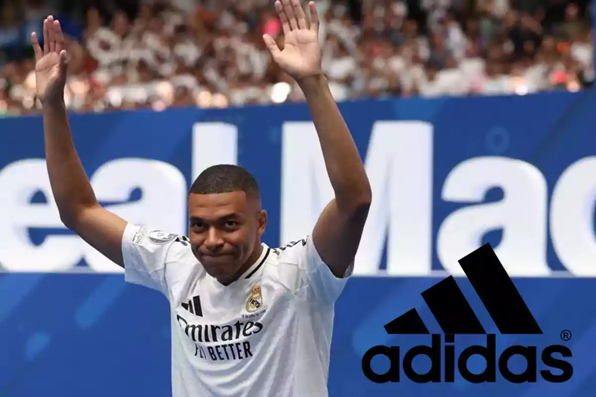 Jugador de fútbol con camiseta blanca del Real Madrid levantando los brazos en señal de saludo, con el logo de Adidas en la esquina inferior derecha.