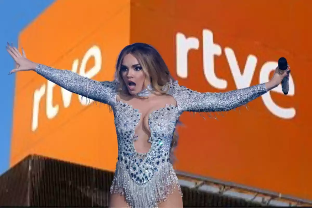 Una persona con un traje brillante y micrófono en mano está frente a un fondo con el logo de RTVE.