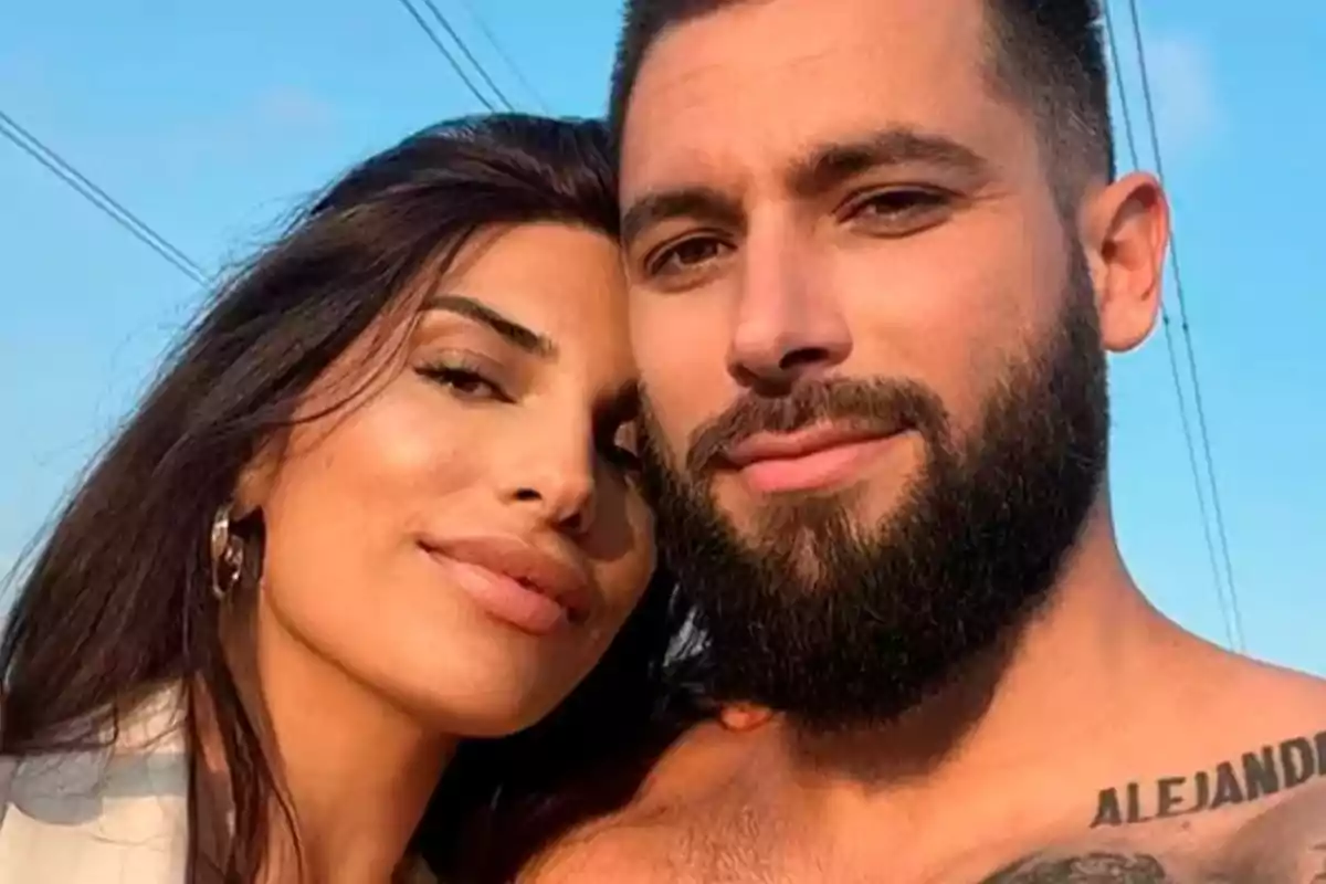 Una pareja sonriente posando al aire libre bajo un cielo azul. Una pareja sonriente posando al aire libre bajo un cielo azul.