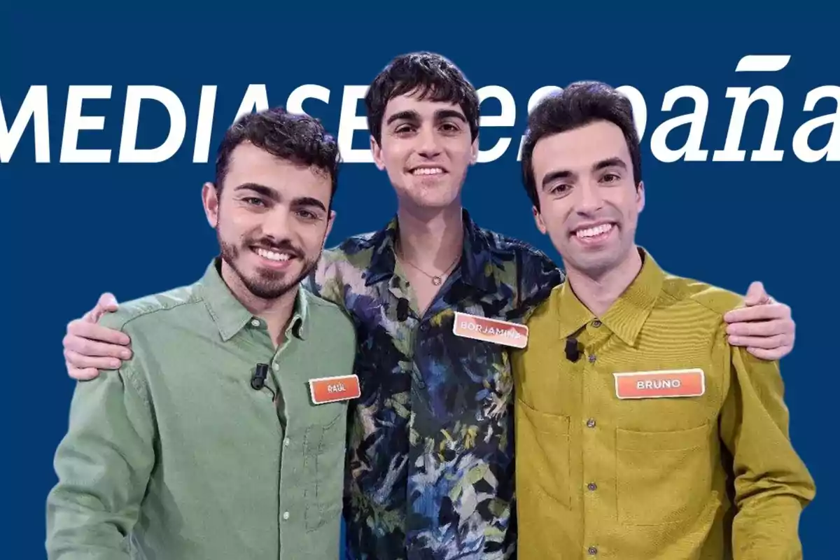 Tres personas posando juntas frente a un fondo azul con el logo de Mediaset España.