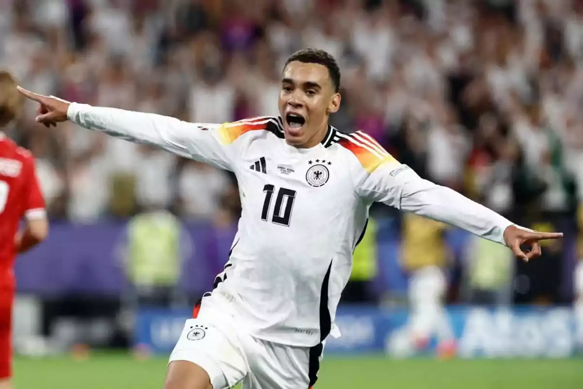 Jugador de fútbol con la camiseta de la selección de Alemania celebrando un gol con los brazos extendidos.