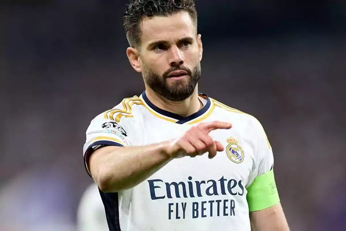 Jugador de fútbol con uniforme blanco del Real Madrid señalando con el dedo.