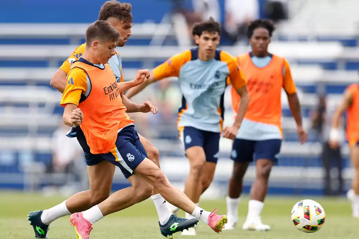 Jugadores de fútbol entrenando en un campo mientras compiten por el balón.