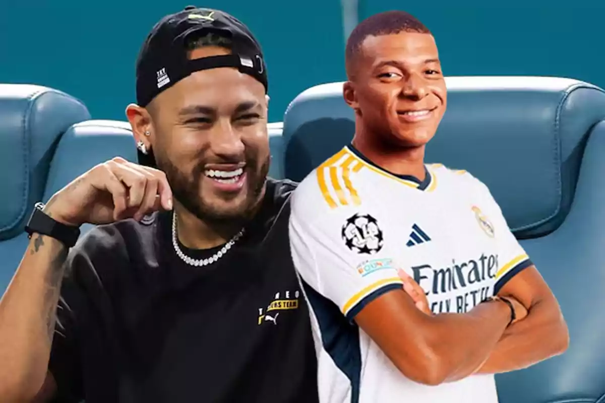 Dos hombres sonrientes, uno con camiseta negra y gorra, el otro con camiseta de fútbol blanca, sentados en asientos de estadio.