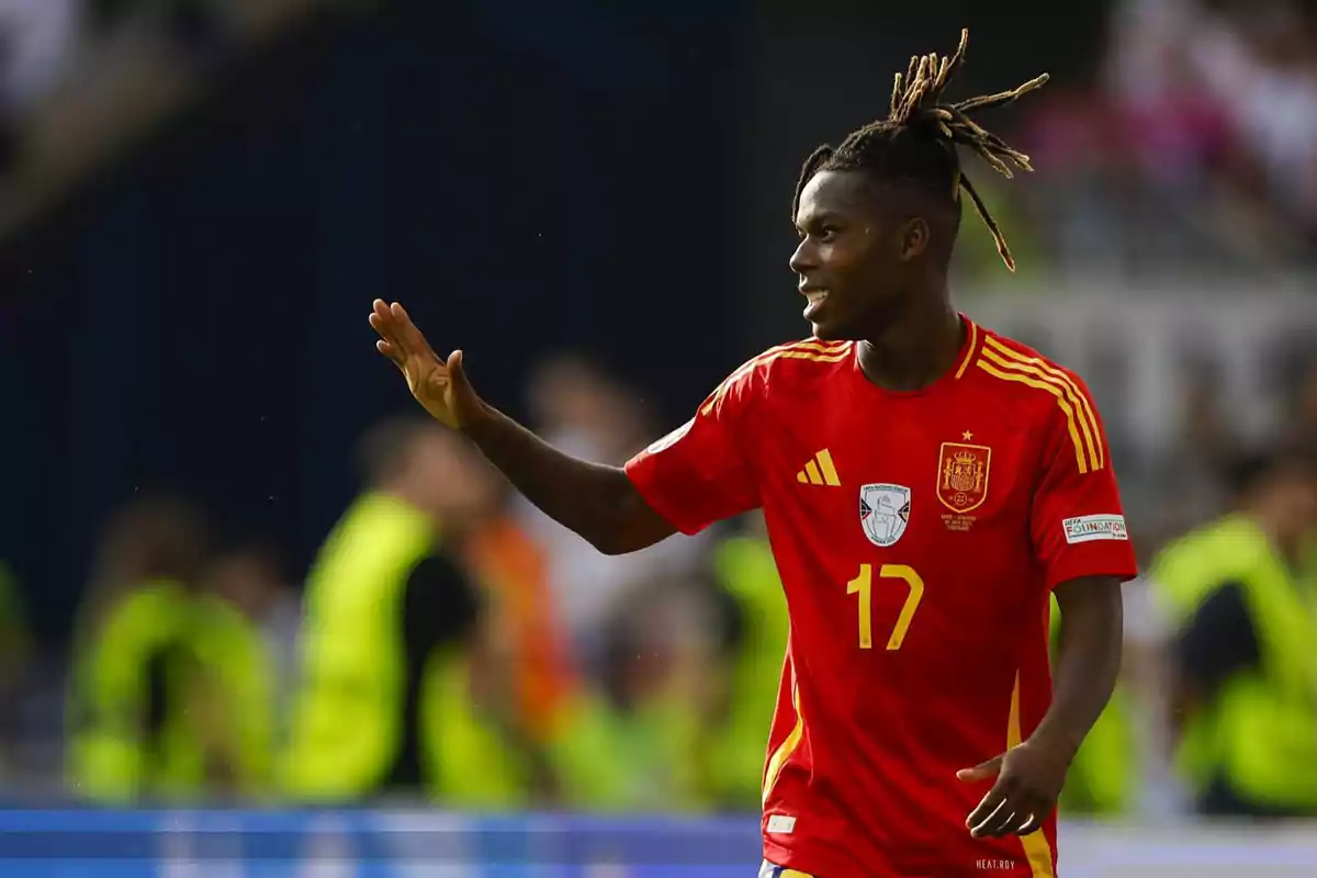 Jugador de fútbol con la camiseta roja de la selección española, número 17, saludando en el campo.