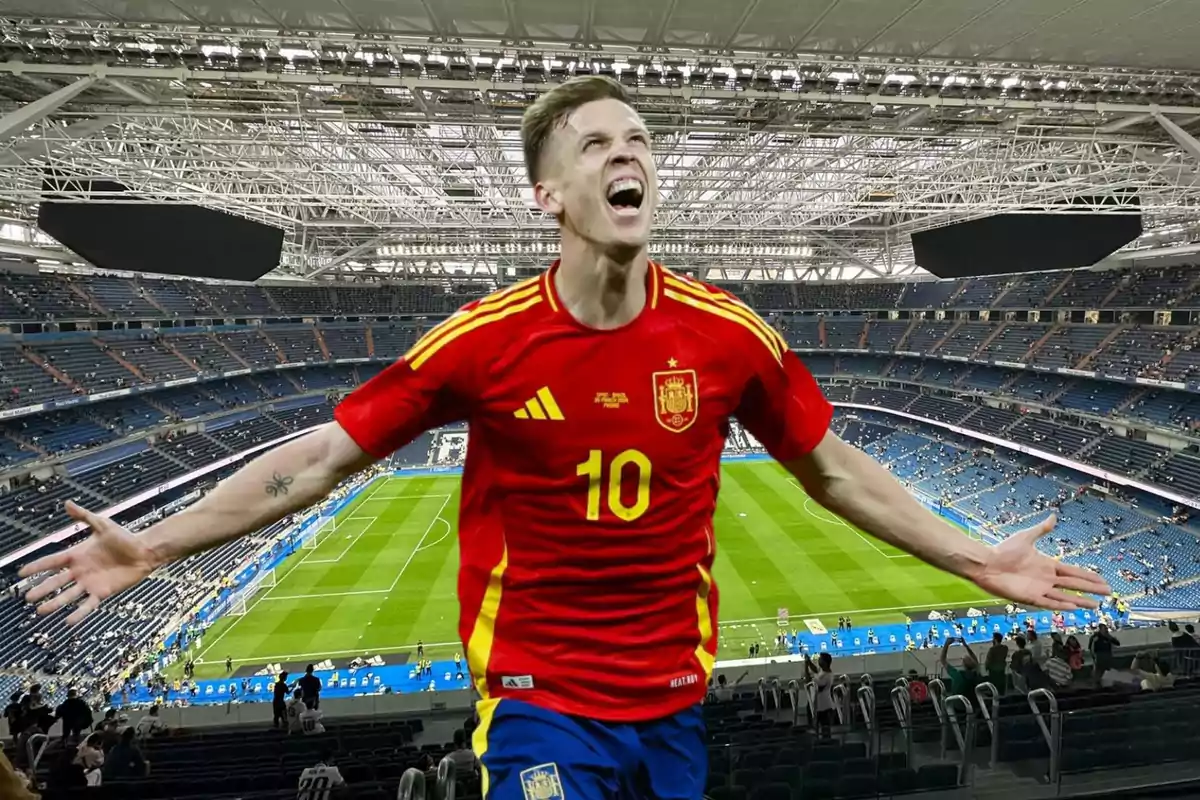 Un jugador de fútbol con la camiseta roja de la selección española celebra con los brazos abiertos en un estadio de fútbol.