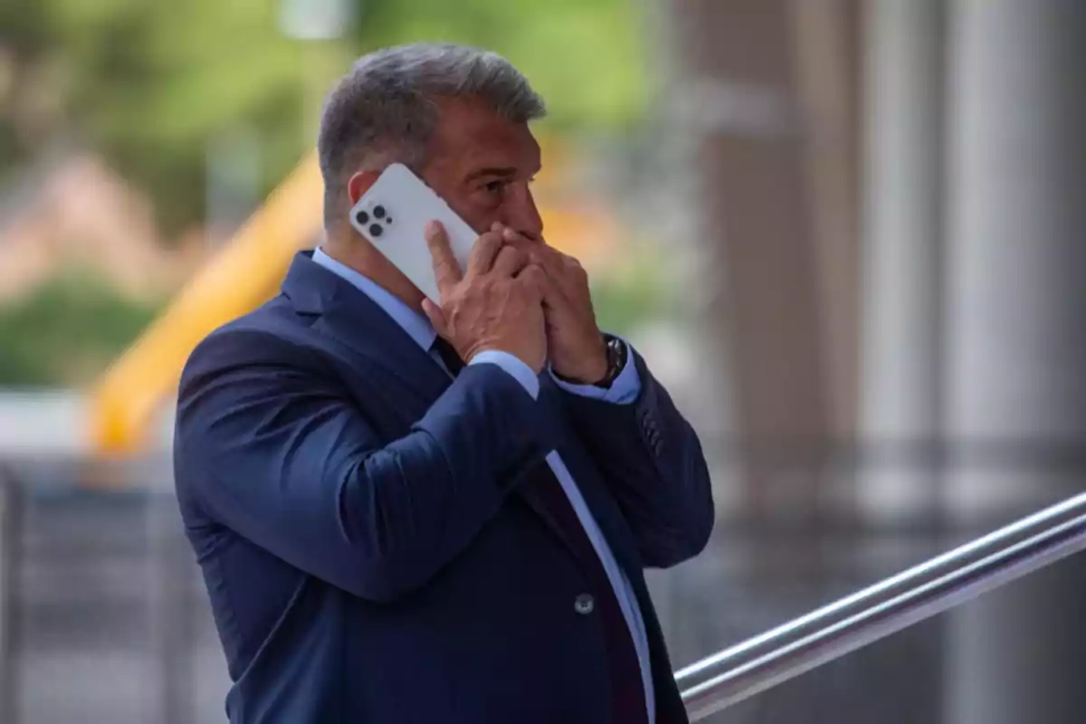 Hombre de traje hablando por teléfono móvil en un entorno urbano.